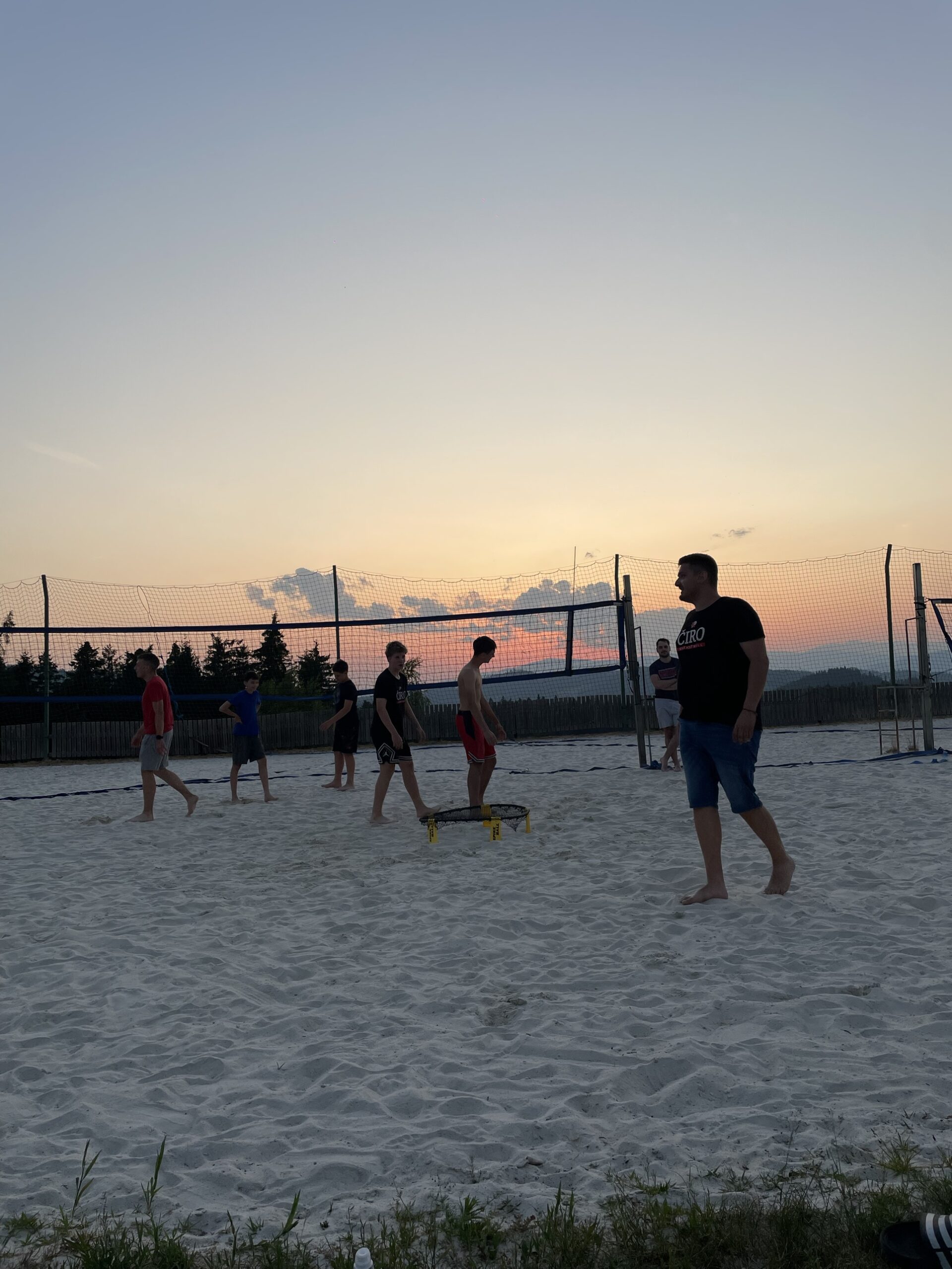 Skupina pri igri spikeball ob zahodu sonca